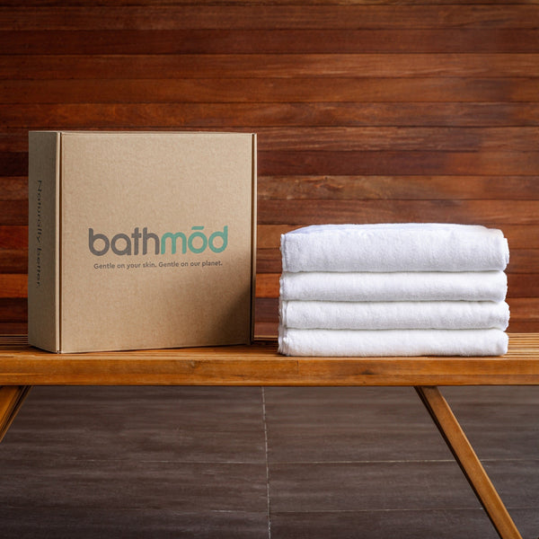 Four plush GOTS-certified organic cotton bath towels stacked and folded